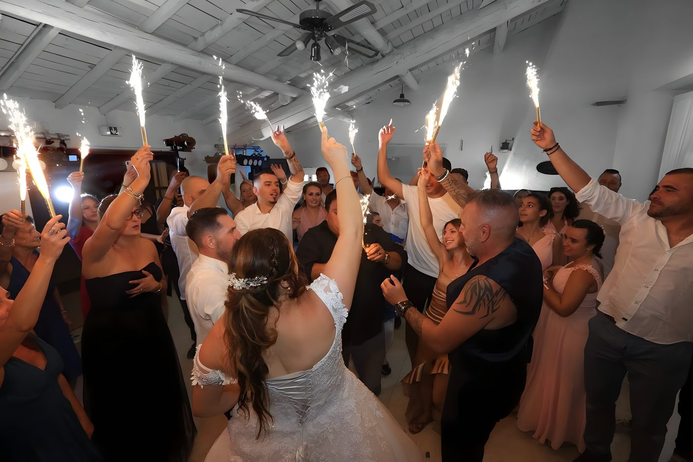 Les invités entourent la mariée en brandissant des cierges magiques allumés au-dessus de la piste